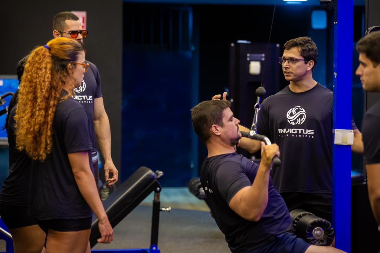 Wilson corrigindo a execução de um aluno no equipamento de puxada